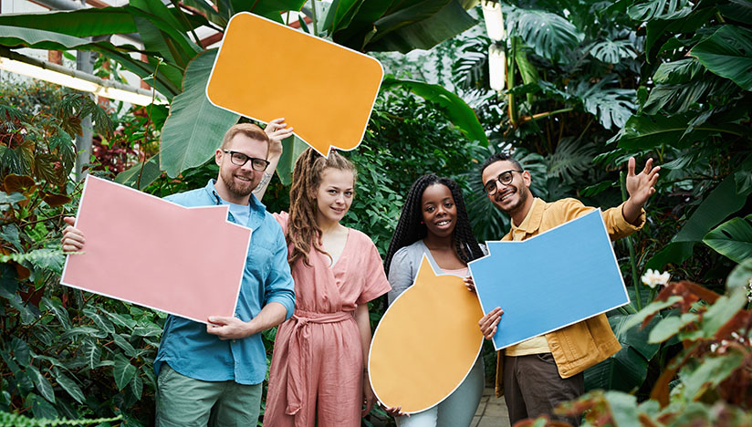 A group of people smiling, holding word bubbles